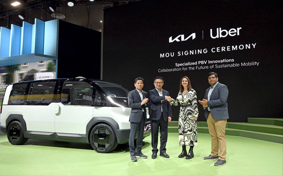 Executives from Kia and Uber Technologies, including Yoon Seung-kyu, second from left, CEO of Kia North America, and Susan Anderson, third from left, global head of Uber's business development team, pose for a photo with Kia's PV5 at its booth at CES 2024 in Las Vegas on Wednesday. [KIA]