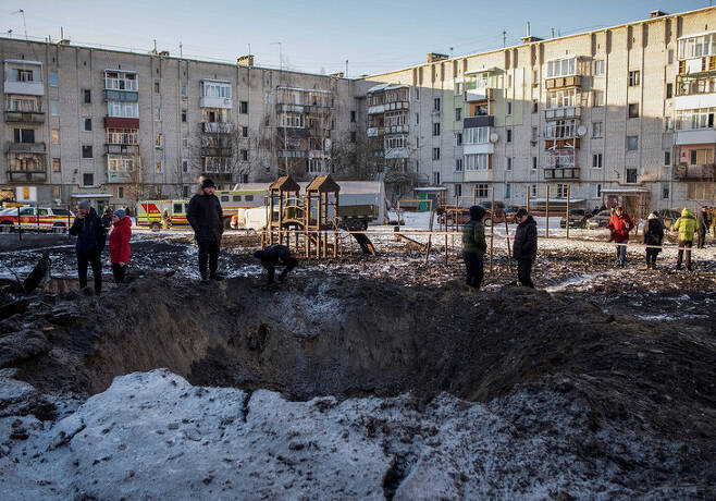 우크라이나 북부 수미주의 쇼스트카 주민들이 13일(현지시각) 러시아군의 공격으로 생긴 웅덩이를 살피고 있다. 쇼스트카/로이터 연합뉴스