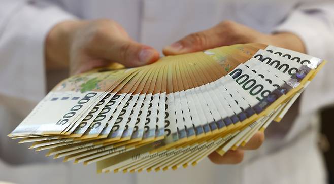 한 은행 직원이 5만원권을 펼쳐 보이고 있다. 연합뉴스