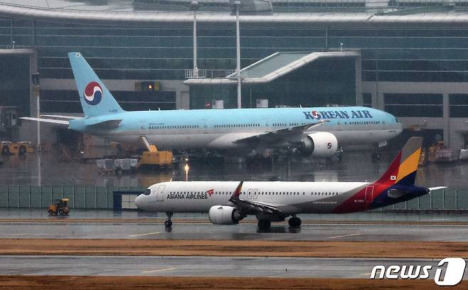 14일 오후 인천국제공항 계류장에 세워진 대한항공 항공기 앞으로 아시아나 항공기가 지나가고 있다. 2024.1.14/뉴스1 ⓒ News1 장수영 기자