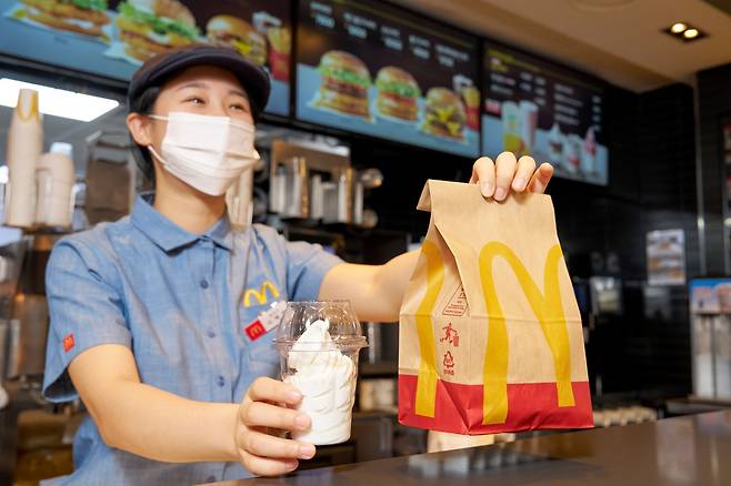 맥도날드 매장 직원이 친환경 재생페트(rPET) 컵에 담긴 '선데이 아이스크림'을 고객에게 건네고 있다. [한국맥도날드 제공]