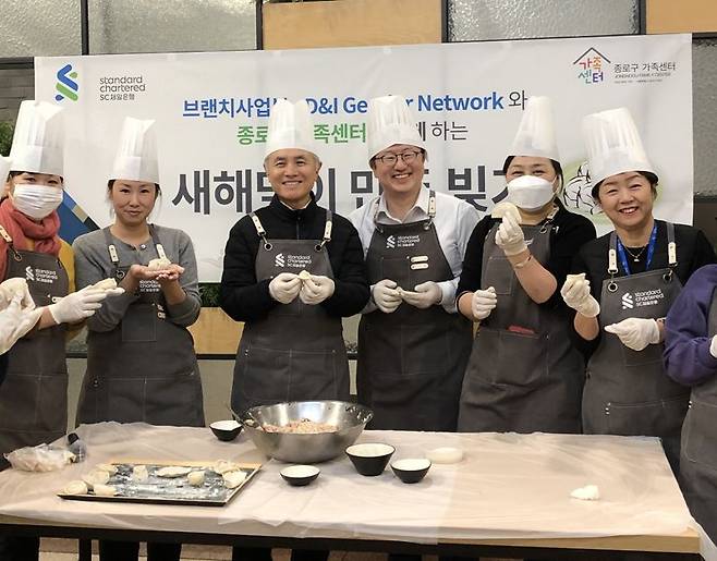 지난 15일 서울 종로구 SC제일은행 본사에서 진행된 ‘새해 만두 빚기 행사’에서 박종복 SC제일은행장(왼쪽 세 번째)과 임직원 자원봉사자들이 종로구 다문화 가족들과 함께 만두를 빚고 있다. 사진=SC제일은행 제공