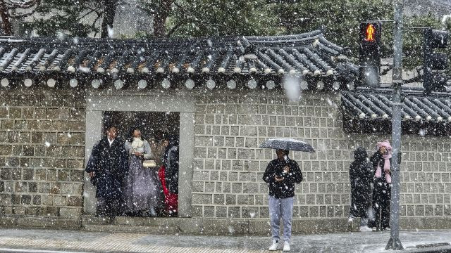 서울 지역에 함박눈이 내리고 있는 17일 오후 서울 종로구 경복궁 앞에서 관광객들이 한복을 입고 건널목에 서 있다. 연합뉴스