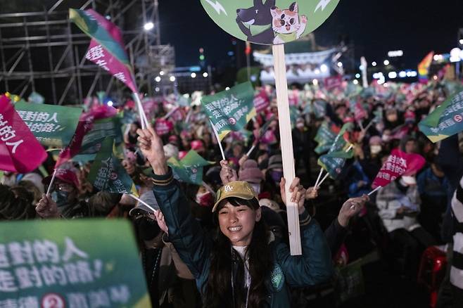 11일 대만 타이베이시 카이거란대로에서 열린 민진당 유세에서 지지자들이 ‘올바른 사람을 선택하고, 올바른 길을 가세요’라고 적힌 깃발을 흔들고 있다. 노란 모자를 쓴 유권자는 녹색 야구점퍼를 입은 모습이다. 이 외투는 민진당이 선거 기간 판매한 공식 굿즈다. 타이베이=AP 뉴시스