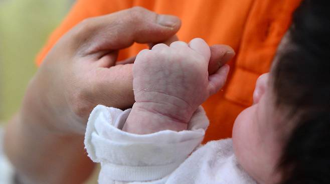 A baby holds the hand of a caregiver at a shelter operated by Eastern Social Welfare Society in Seodaemun-gu, Seoul in 2017. (Newsis)