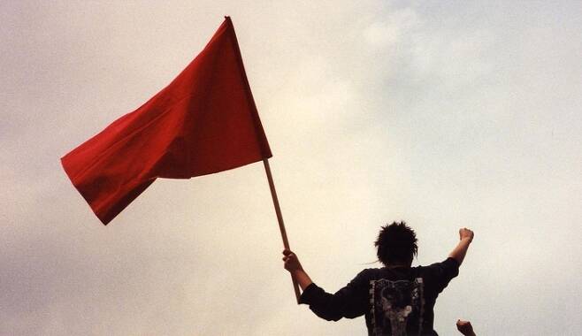 붉은 깃발을 든 한 남성의 모습. [Wikimedia Commons]