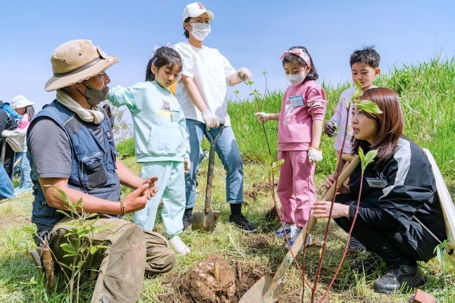 우리은행 임직원 가족들이 봄맞이 노을공원 숲 조성 봉사활동에 참여해 묘목을 심기 전 시민단체 활동가로부터 설명을 듣고 있다.ⓒ우리은행