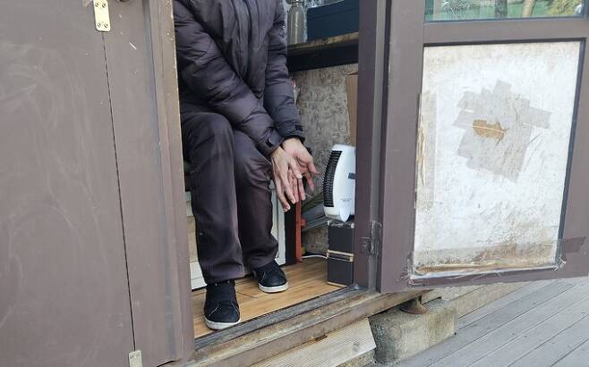 체감온도가 영하 20도까지 떨어진 23일 서울 서초구 한 식당 주차관리인이 난방 기기에 손을 대고 있다. 주차관리인은 “직원 3명이 돌아가며 작은 난방 기기 하나에 의존해 추위를 버티고 있다”고 토로했다. 안경준 기자