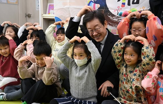 24일 경기 김포시 통진읍 청룡어린이집을 찾은 이재명 더불어민주당 대표가 어린이집 원아들과 함께 손 하트를 만들며 밝게 웃고 있다. 사진 국회사진기자단