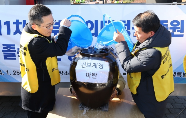 이필수(왼쪽) 범의료계대책특별위원회 위원장 겸 대한의사협회장이 25일 서울 용산 대통령실 앞에서 열린 제1차 정부의 의대정원 증원 졸속추진 강력 규탄 집회에서 건보재정 파탄 퍼포먼스를 하고 있다. 뉴시스