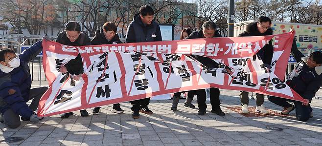 민주노총과 생명안전행동 관계자들이 26일 오전 서울 용산 대통령실 앞에서 중대재해처벌법 시행 2년 기자회견을 열고 제대로 된 법 집행을 촉구하며 현수막을 찢는 퍼포먼스를 하고 있다. 연합뉴스