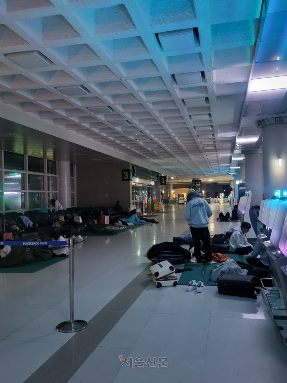 지난 23일 폭설과 강풍으로 제주공항을 오가는 항공편 결항이 속출하자 대체 항공편을 구하지 못한 승객들이 이튿날 선착순 예약을 위해 공항에서 노숙을 하고 있다.