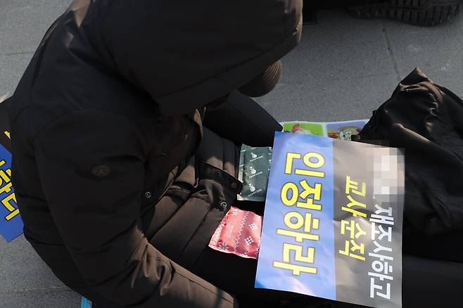 한 참가자가 서초구 한 초등학교 교사 사건의 재조사를 요구하는 손팻말로 추위를 막고 있다. 강창광 기자