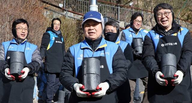 25일 서울시 서대문구 홍제동에 위치한 개미마을에서 '사랑의 연탄 나눔' 행사에 참석한 정지호(왼쪽) 신한파트너스 사장, 진옥동(가운데) 신한금융그룹 회장, 이동현(오른쪽) 신한벤처투자 사장과 임직원 봉사자들이 연탄을 나르고 있다. /신한금융