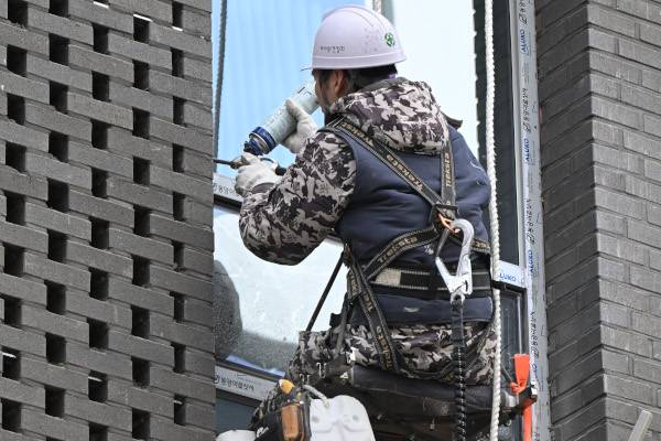 건설노동자가 28일 서울 서초구의 한 공사현장에서 건물 외벽에 매달려 작업을 진행하고 있다. 5인 이상 50인 미만 사업장에도 지난 27일부터 중대재해처벌법이 확대 적용됐다. 윤웅 기자