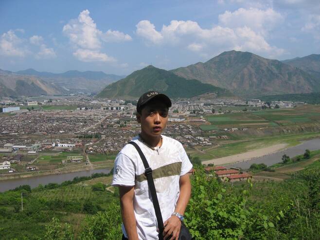 2004년 8월 백두산 배낭여행을 떠난 강 씨. 강 너머 보이는 마을이 그가 태어난 고향 함북 무산이다.