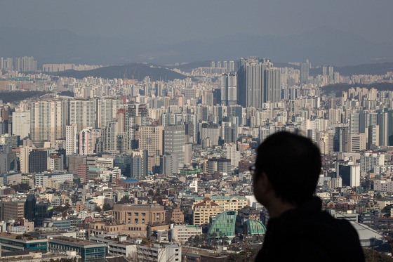 A pedestrian looks at apartment buildings from Mount Namsan in central Seoul on Sunday. [NEWS1]