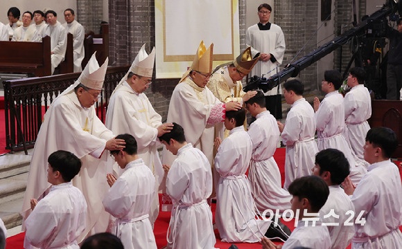 1일 서울 중구 명동대성당에서 열린 2024년 천주교 서울대교구 부제 서품식에서 부제 수품자들이 정순택 대주교를 비롯한 교구 주교·사제단에게 안수받고 있다. [사진= 사진공동취재단]