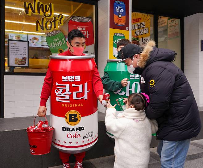 2021년 송현석(왼쪽) 신세계푸드 대표이사가 서울 중구 무교동 노브랜드 버거 서울시청점 매장 앞에서 ‘콜라맨’ 복장을 하고 시민에게 캔음료를 나눠주고 있다[신세계푸드 제공]