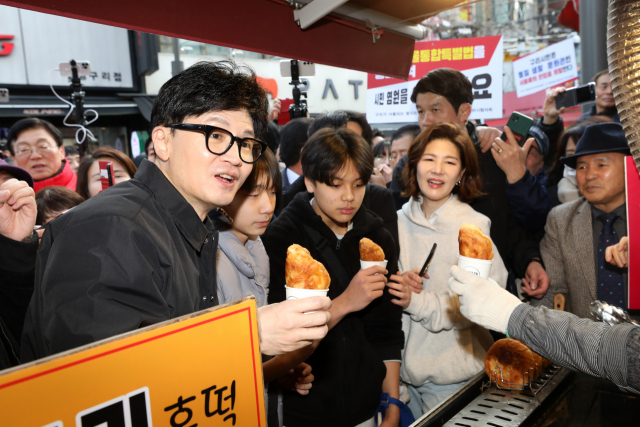 한동훈(앞줄 왼쪽) 국민의힘 비상대책위원장이 설 명절을 앞둔 2일 경기도 구리전통시장을 방문해 호떡을 구입한 뒤 상인과 대화하고 있다. 연합뉴스