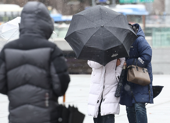 전국에 비와 눈이 내리는 5일 오후 서울 광화문광장에서 시민들이 눈과 바람을 맞으며 걸어가고 있다. 〈사진=연합뉴스〉