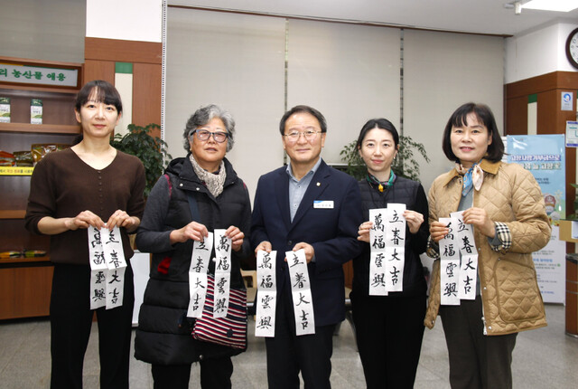 강선욱 경남 함양농협 조합장(가운데)이 고객·직원들과 함께 입춘첩을 들어보이고 있다.·