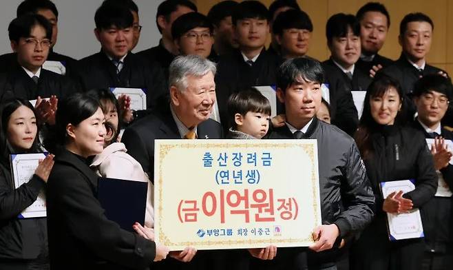 Booyoung Group Chairman Lee Dae-geun (front row, center) presents a childbirth subsidy to a multi-generational family during a ceremony at the Booyoung Building in Jung-gu, Seoul, on Friday morning. Yonhap