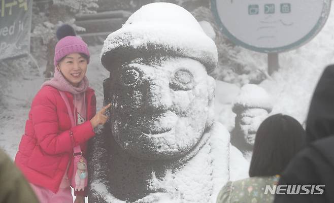 [제주=뉴시스] 우장호 기자 = 제주 산간에 눈이 내린 6일 오전 한라산 1100도로 휴게소를 찾은 관광객들이 눈을 뒤집어쓴 돌하르방과 기념촬영하며 즐거운 시간을 보내고 있다. 2024.02.06. woo1223@newsis.com