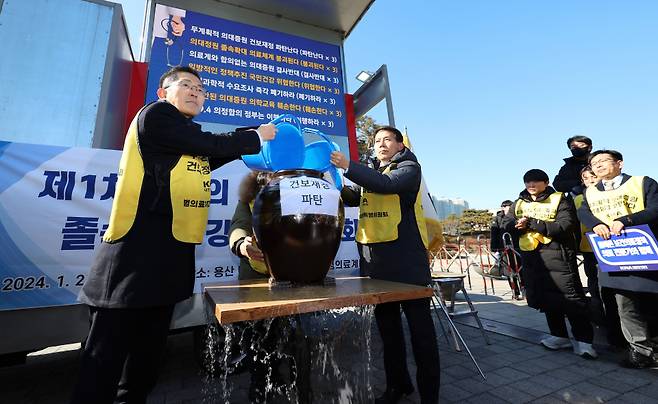 이필수 범의료계대책특별위원회 위원장(의협 회장, 왼쪽)과 참석자들이 1월25일 용산 대통령실 앞에서 정부의 의대 증원 추진을 규탄하는 집회를 열고 구멍 난 항아리에 물을 붓는 퍼포먼스를 하고 있다. ⓒ 연합뉴스