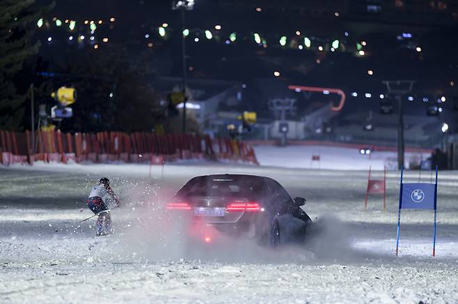 BMW 뉴 i5 M60 xDrive와 스키 선수가 활강 및 회전 대결을 펼치는 영상 화면.