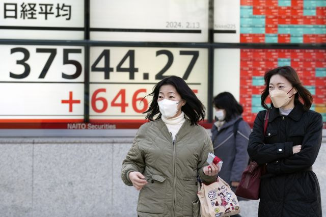 일본 도쿄 시민들이 13일 한 증권사 외벽에 설치된 닛케이지수 전광판 앞을 지나고 있다. AP연합뉴스