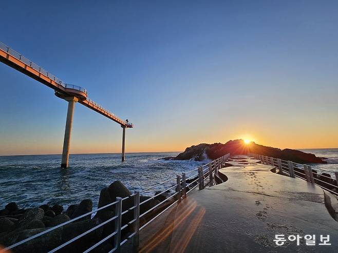 울진 후포항 등기산 스카이워크가 왼쪽 위로 보이는 갓바위 공원에 해가 떠오르고 있다.