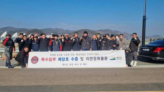 특수임무유공자회 예산군지회가 수중 정화활동 후 기념촬영하고 있다.사진=예산군 제공