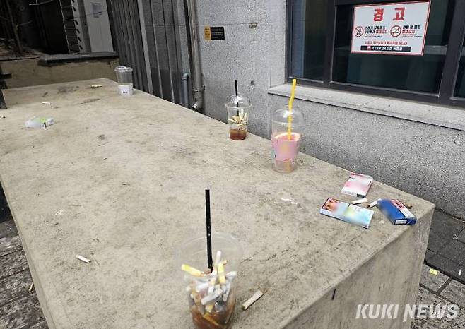 담배꽁초 및 쓰레기 투기 금지 안내문이 부착된 곳에 버려진 쓰레기들. 사진=임지혜 기자