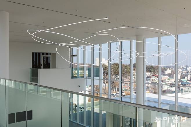 미술관 2층 천장에 설치된 루치오 폰타나의 네온 작품 뒤로 외부 경관을 볼 수 있는 조망 공간이 있는 미술관의 모습. ⓒ 솔올미술관