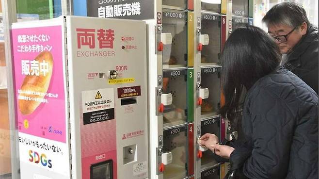 일본 '남은 빵 자판기'를 이용하고 있는 모습. 자판기에 동전을 넣고 있다.