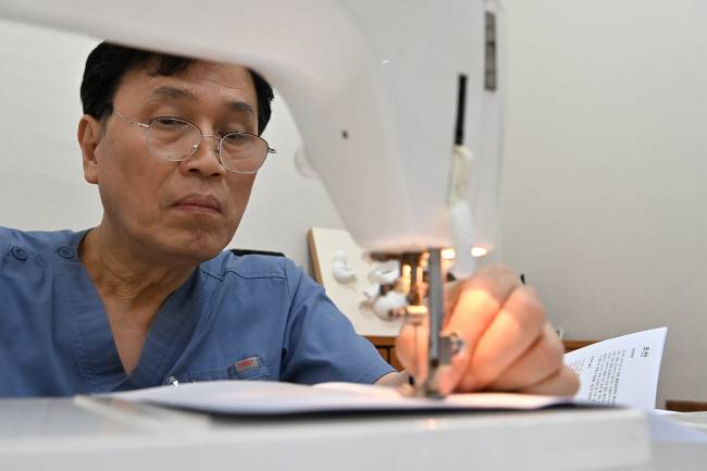 심상덕 진오비산부인과 원장이 직접 재단한 종이를 재봉틀로 박음질하고 있다. 백동현 기자