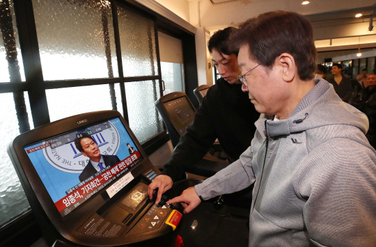 이재명 더불어민주당 대표가 28일 오전 서울 서대문구 매직짐 휘트니스에서 러닝머신을 이용하는 중, 화면에 임종석 전 대통령비서실장의 공천 관련 기자회견 모습이 보이고 있다. 뉴시스(사진공동취재단)