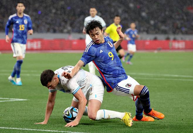 일본 축구대표팀 미토마가 지난해 우루과이와의 평가전에서 볼경합을 하다 넘어지고 있다. Getty Images코리아