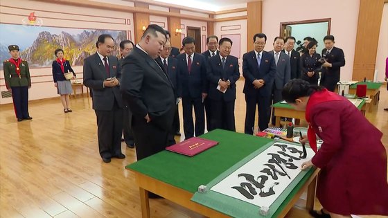 김정은 북한 국무위원장이 지난 1월 1일 만경대학생소년궁전에서 열린 '2024년 설맞이 공연' 관람에 앞서 한 학생이 '만리경1호' 글귀를 붓글씨로 쓰는 모습을 보고 있다. 조선중앙TV 화면=연합뉴스