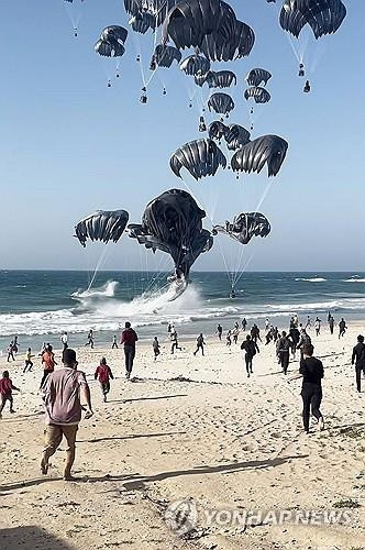 공중에서 투하된 식량을 향해 달려가는 가자지구 주민들 [AFP = 연합뉴스]