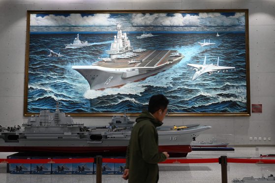 지난 3일 중국 베이징에 있는 군사박물관에서 중국의 첫 항공모함인 랴오닝함 그림 앞을 한 시민이 지나가고 있다. AFP=연합뉴스