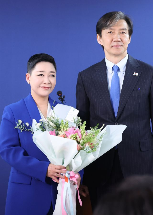 가수 리아(본명 김재원)가 11일 여의도 조국혁신당 당사에서 열린 입당 환영식에서 조국 대표로부터 꽃다발을 받고 포즈를 취하고 있다. 연합뉴스