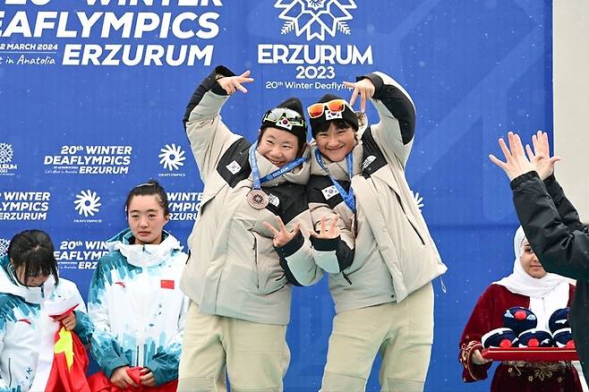 대한민국 데플림픽 크로스컨트리 대표팀 김관-이선주(가운데)가 2023 에르주름 동계데플림픽 크로스컨트리 여자 팀 스프링트에서 동메달을 따낸 후 포즈를 취하고 있다. 사진 | 한국농아인스포츠연맹