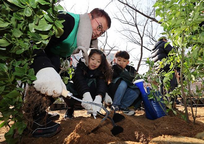 영등포구민(왼쪽부터)과 임유진(8)양, 송원빈(8)군이 13일 오전 서울 영등포구 오목교 인근 안양천 산책로에서 열린 \'릴레이 나무 심기\' 행사에서 산수국을 심고 있다. 김영원 기자