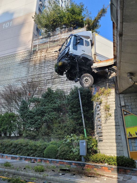 13일 오전 9시 37분쯤 부산 동구 좌천동 고가도로를 달리던 트럭이 난간을 뚫고 허공에 매달린 채 멈춰있다. 부산 동부경찰서 제공