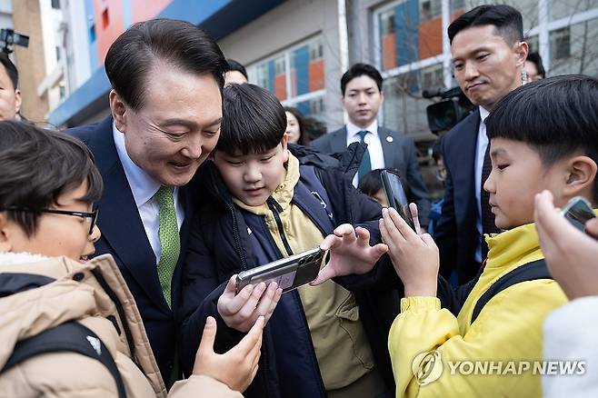 초등학교 방문 마친 윤석열 대통령 (무안=연합뉴스) 홍해인 기자 = 윤석열 대통령이 14일 전남 무안군 오룡초등학교 도서관에서 늘봄학교 간담회를 마친 뒤 학교를 떠나며 학생들과 기념사진을 찍고 있다. 2024.3.14 [대통령실 제공. 재판매 및 DB 금지] hihong@yna.co.kr