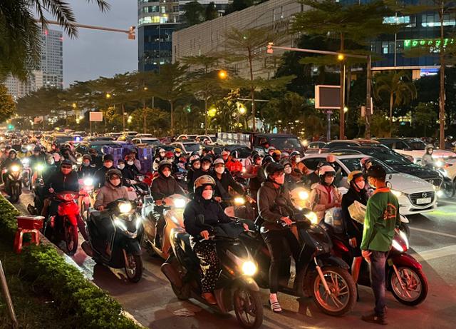 베트남 수도 하노이 시내 퇴근길 풍경. 헬멧과 마스크를 착용한 여성들이 남성들 틈에 끼어 오토바이로 퇴근하고 있다. 하노이=허경주 특파원