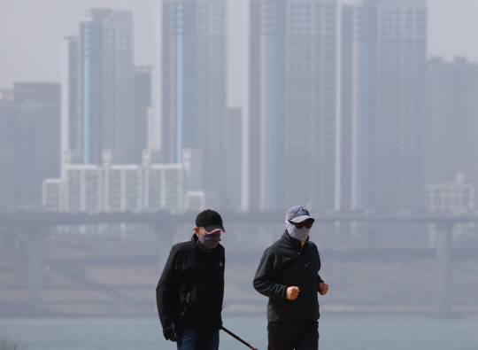 올봄 첫 황사 유입으로 미세먼지 수준이 나쁨을 기록한 지난 17일 서울 잠실한강공원을 찾은 시민들이 마스크를 쓰고 산책하고 있다. 연합뉴스