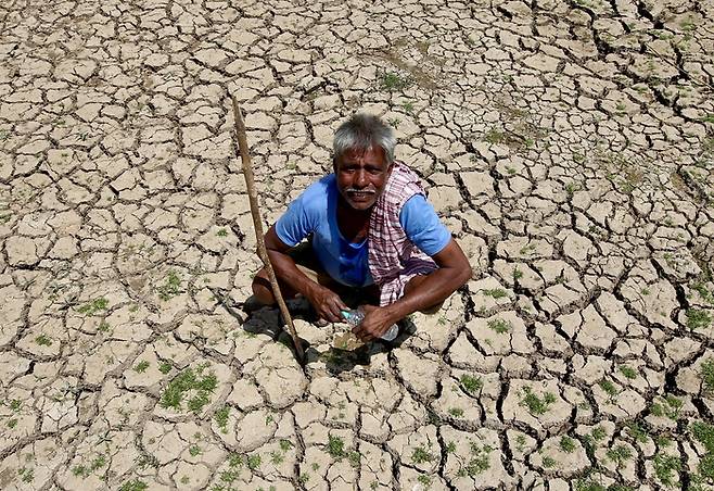지난 1일(현지시간) 가뭄으로 말라붙은 인도 남부 카르나타카주 벵갈루루의 한 호수 바닥에 한 남성이 앉아 있다. EPA연합뉴스